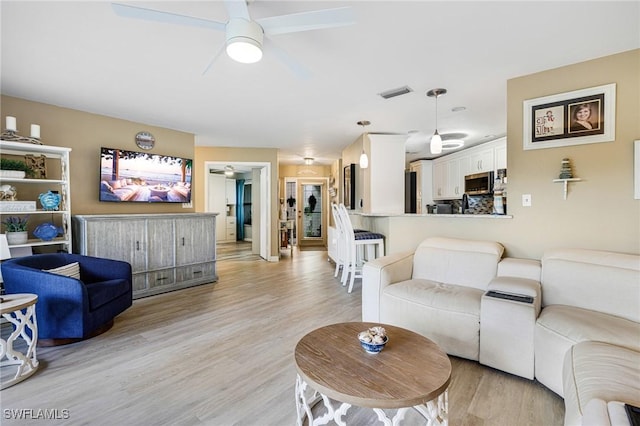 living room featuring ceiling fan and light wood-type flooring