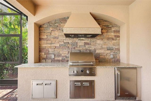 kitchen featuring fridge, light stone countertops, and custom range hood