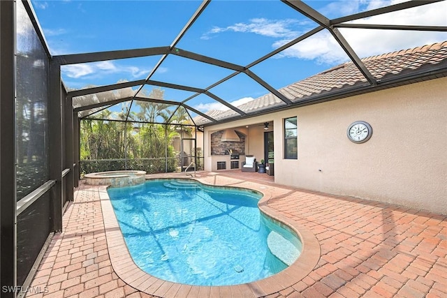 view of swimming pool with an in ground hot tub, an outdoor kitchen, glass enclosure, and a patio area