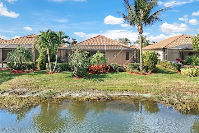 rear view of property featuring a lawn, a water view, and glass enclosure