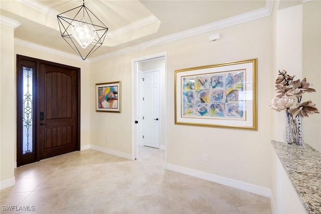 entrance foyer with ornamental molding, a tray ceiling, and a chandelier