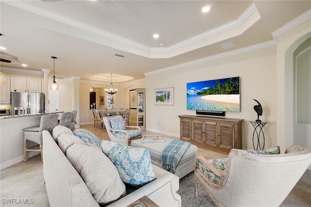 living room with a notable chandelier, a tray ceiling, and ornamental molding