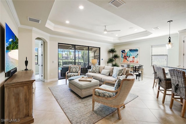 living room with crown molding, ceiling fan, a raised ceiling, and light tile patterned floors