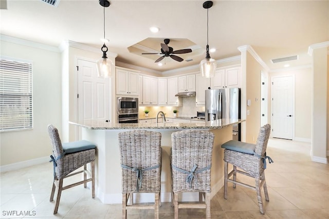 kitchen with light stone counters, appliances with stainless steel finishes, decorative light fixtures, and white cabinets