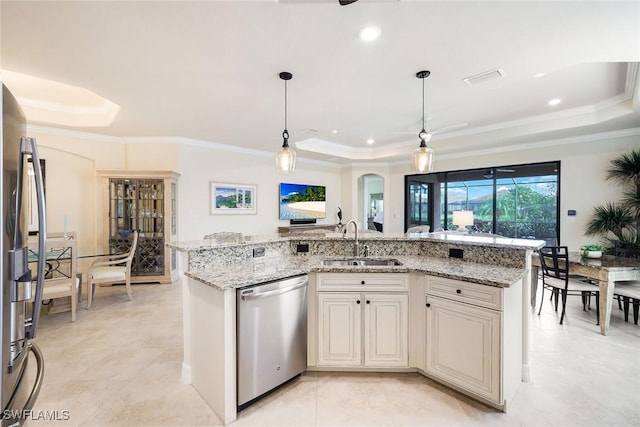 kitchen featuring a kitchen island with sink, sink, a tray ceiling, and stainless steel appliances