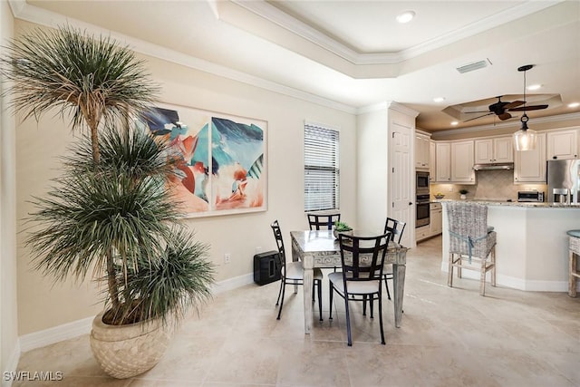 dining area featuring ceiling fan, ornamental molding, and a tray ceiling