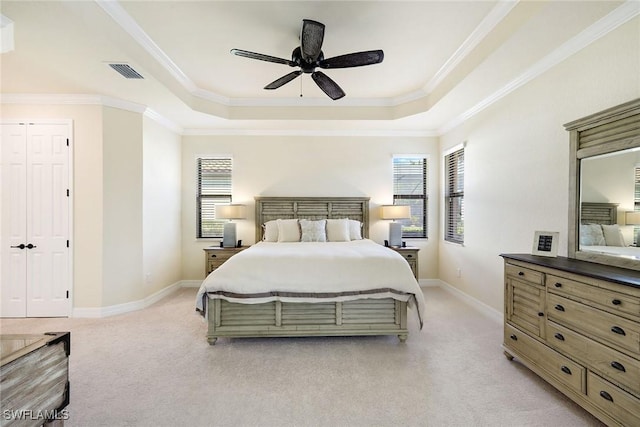 bedroom featuring light colored carpet, a tray ceiling, and multiple windows