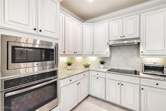 28131 Edenderry Ct, Bonita Springs, FL 34135 - kitchen featuring appliances with stainless steel finishes, under cabinet range hood, white cabinets, decorative backsplash, and light stone countertops