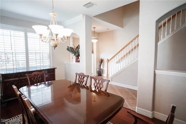 dining area with light tile patterned flooring, ornamental molding, and a chandelier