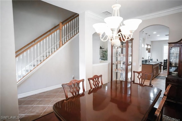 tiled dining space with sink, crown molding, and a chandelier