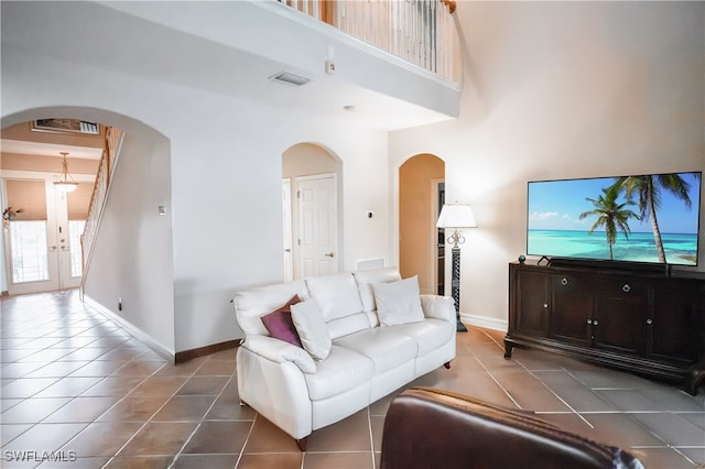 tiled living room featuring a high ceiling and french doors