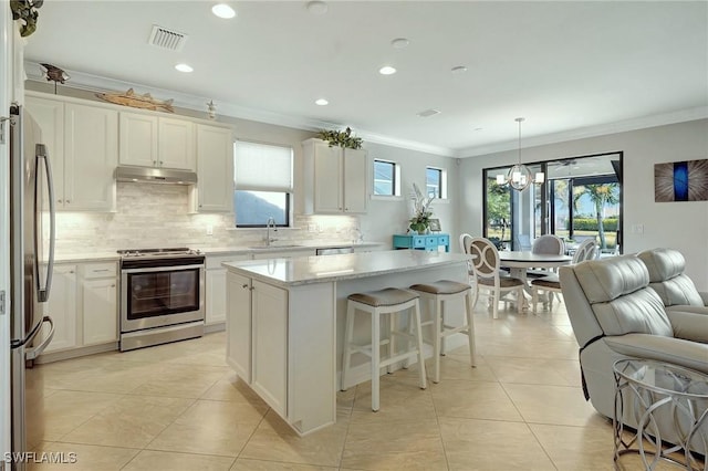 kitchen featuring sink, white cabinetry, stainless steel appliances, a center island, and decorative light fixtures