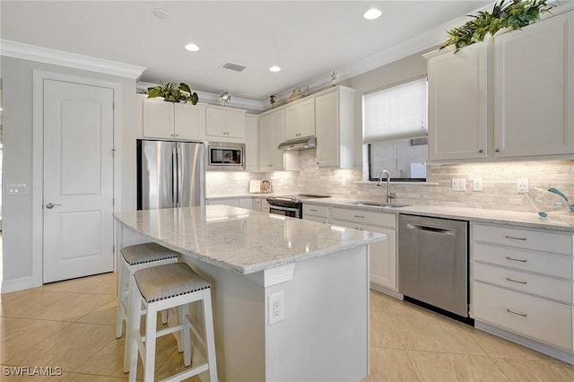 kitchen with sink, a center island, ornamental molding, appliances with stainless steel finishes, and white cabinets