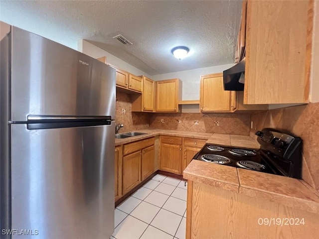 kitchen with sink, extractor fan, light brown cabinets, stainless steel refrigerator, and electric range