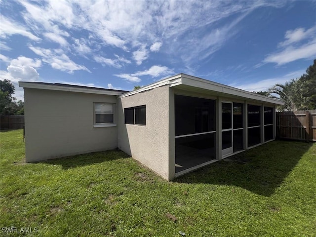 rear view of house featuring a sunroom and a lawn