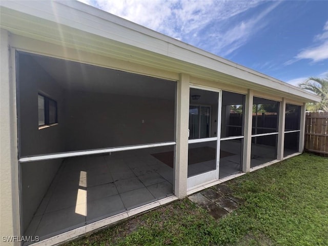 view of side of property with a sunroom and a lawn