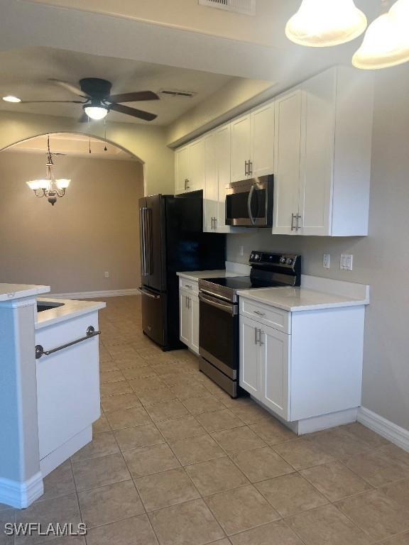 kitchen featuring ceiling fan with notable chandelier, pendant lighting, white cabinets, light tile patterned floors, and stainless steel appliances