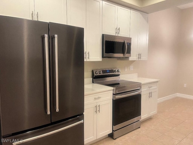 kitchen with white cabinetry, appliances with stainless steel finishes, light stone countertops, and light tile patterned floors