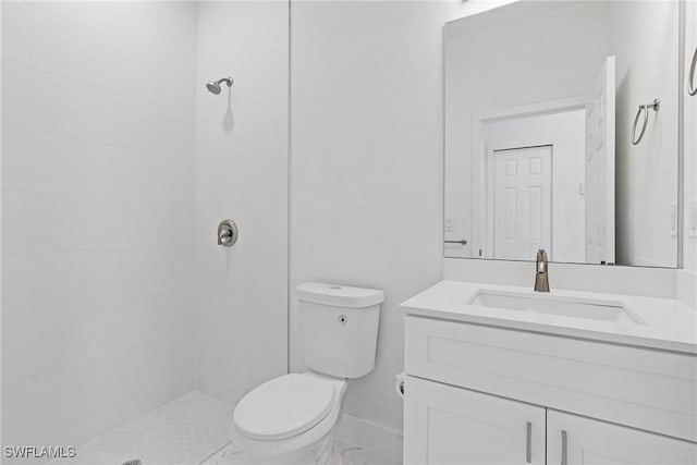 bathroom featuring vanity, toilet, and a tile shower