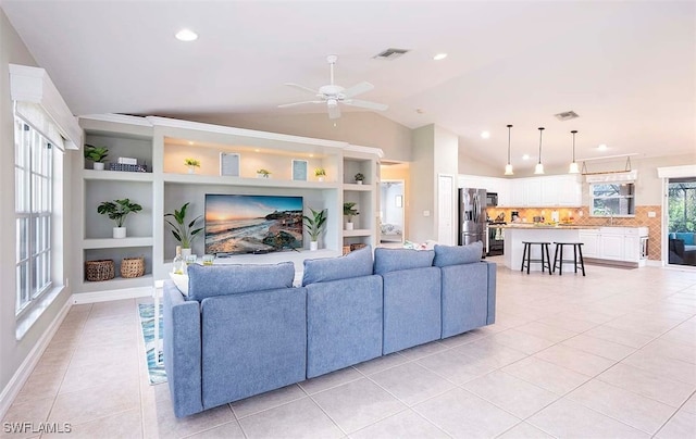 tiled living room featuring vaulted ceiling, sink, ceiling fan, and built in shelves