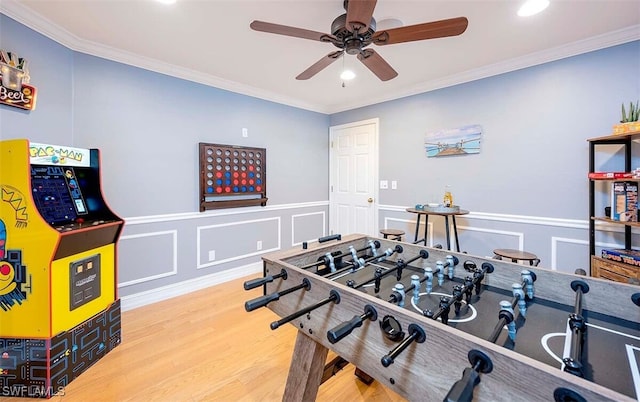 recreation room featuring ceiling fan, ornamental molding, and light hardwood / wood-style flooring