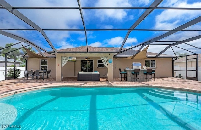 view of pool featuring exterior bar, glass enclosure, ceiling fan, an outdoor living space, and a patio area