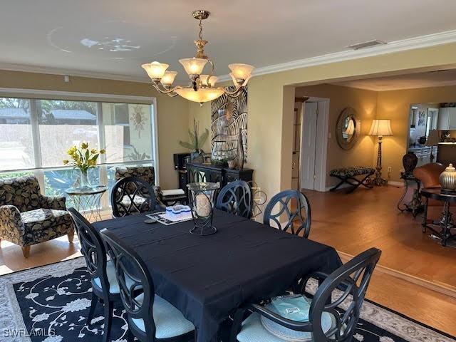 dining space featuring an inviting chandelier, ornamental molding, and wood-type flooring