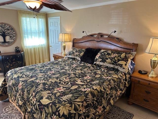 tiled bedroom with ceiling fan and ornamental molding