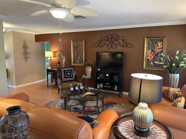 living room featuring ornamental molding, light hardwood / wood-style floors, and ceiling fan