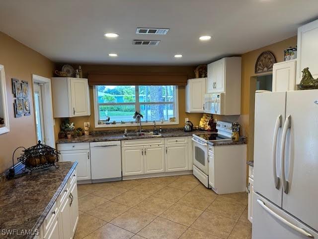 kitchen featuring white cabinetry, sink, white appliances, and light tile patterned floors