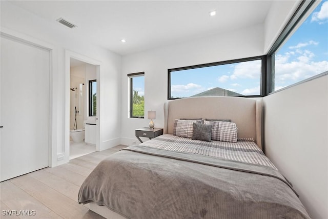 bedroom with ensuite bathroom and light wood-type flooring