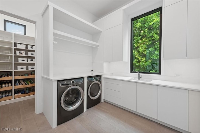 laundry area with cabinets, independent washer and dryer, plenty of natural light, and sink