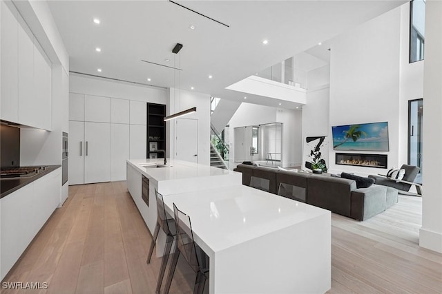 kitchen with light wood-type flooring, a large island, sink, and white cabinets