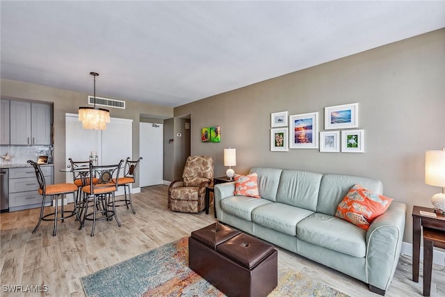 living room featuring a chandelier and light wood-type flooring