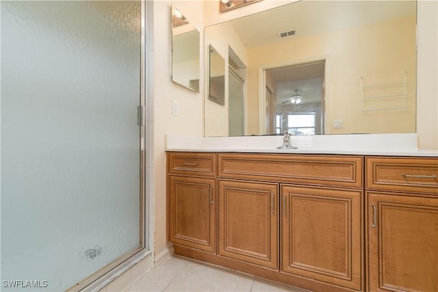 bathroom with a shower with door, vanity, and tile patterned flooring