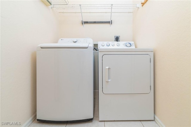 clothes washing area with light tile patterned flooring and independent washer and dryer