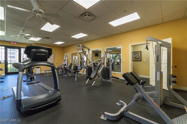 exercise room with ceiling fan and a drop ceiling