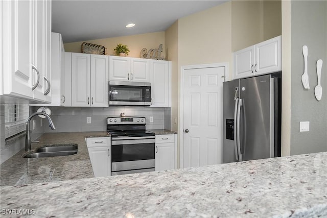 kitchen featuring vaulted ceiling, white cabinetry, sink, decorative backsplash, and stainless steel appliances