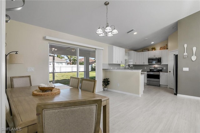 dining space featuring lofted ceiling, sink, an inviting chandelier, and light hardwood / wood-style floors