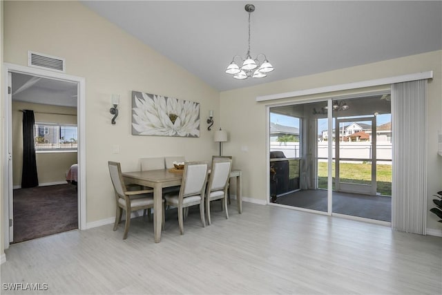 dining room featuring vaulted ceiling, a wealth of natural light, a chandelier, and light hardwood / wood-style flooring