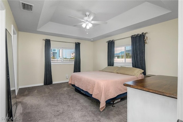 carpeted bedroom featuring a raised ceiling and ceiling fan