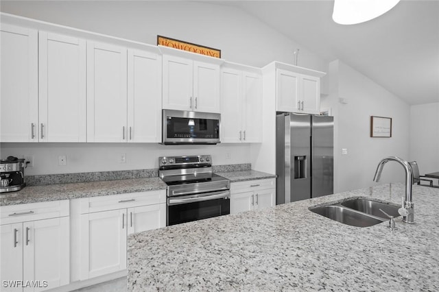 kitchen with vaulted ceiling, stainless steel appliances, sink, and white cabinets