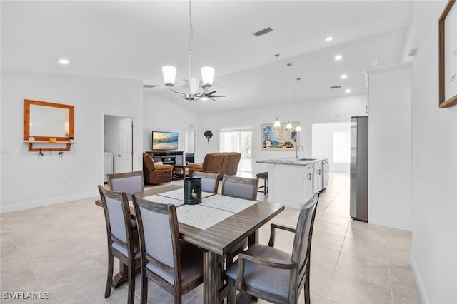 dining area featuring sink, light tile patterned floors, vaulted ceiling, and a chandelier