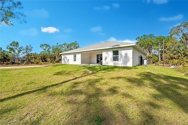 rear view of property with a yard and central AC