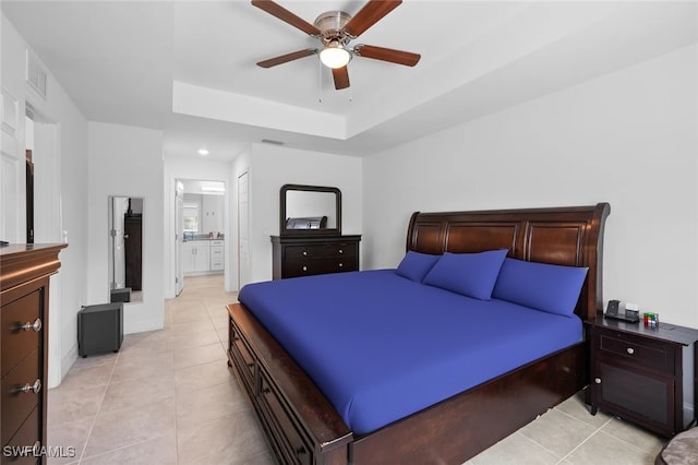 tiled bedroom with ceiling fan, ensuite bathroom, and a tray ceiling