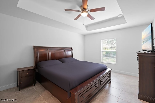 tiled bedroom with a raised ceiling and ceiling fan