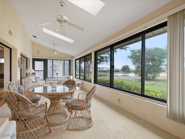 sunroom / solarium with lofted ceiling with skylight, ceiling fan, and a water view