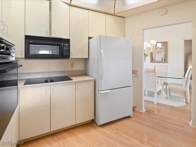 kitchen with pendant lighting, white cabinetry, a notable chandelier, black appliances, and light hardwood / wood-style floors