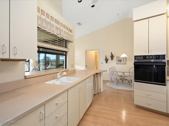 kitchen with sink, light hardwood / wood-style flooring, black oven, dishwasher, and hanging light fixtures