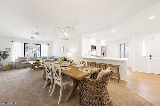 dining area featuring sink, a chandelier, high vaulted ceiling, and light carpet